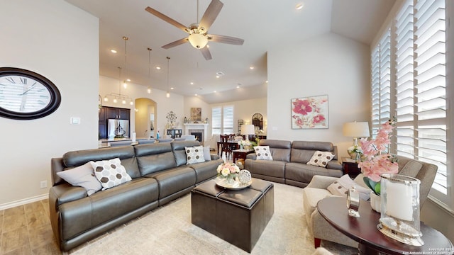 living area with high vaulted ceiling, arched walkways, a fireplace, baseboards, and ceiling fan