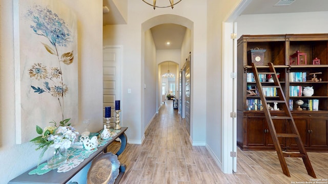 hallway featuring arched walkways, baseboards, and wood tiled floor