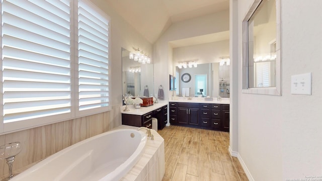 bathroom with vanity, lofted ceiling, a bath, and wood finished floors