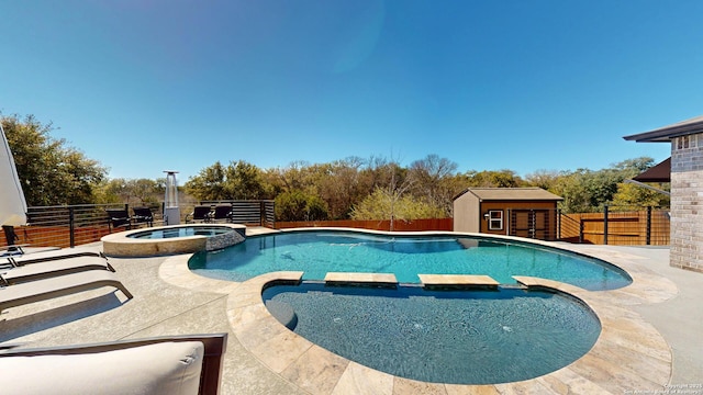 view of pool featuring an outbuilding, a fenced backyard, and a pool with connected hot tub