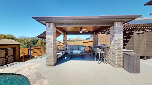 view of patio with outdoor dry bar, an outdoor living space, ceiling fan, and fence