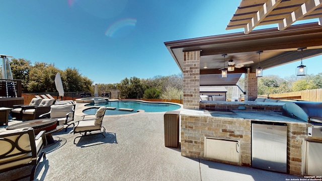 view of swimming pool featuring area for grilling, a pool with connected hot tub, fence, a fire pit, and a patio area