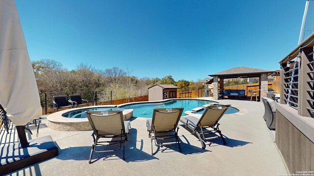 view of pool with a pool with connected hot tub, a gazebo, a fenced backyard, a patio area, and an outbuilding