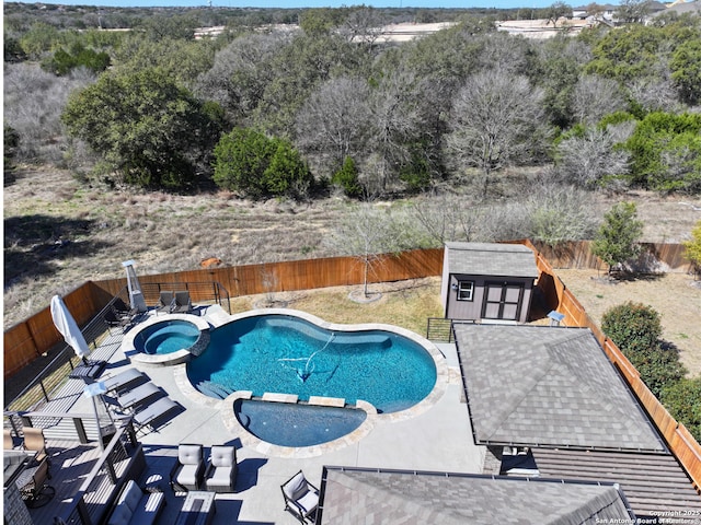 view of swimming pool with a patio, a fenced backyard, a pool with connected hot tub, an outdoor structure, and a storage unit