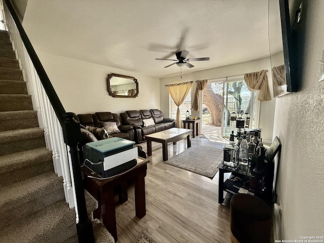 living room with stairway, a textured ceiling, a ceiling fan, and wood finished floors