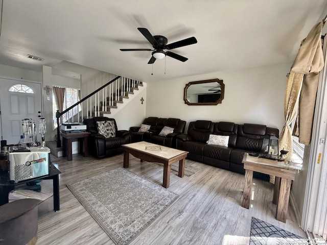 living room with visible vents, stairs, a ceiling fan, and wood finished floors