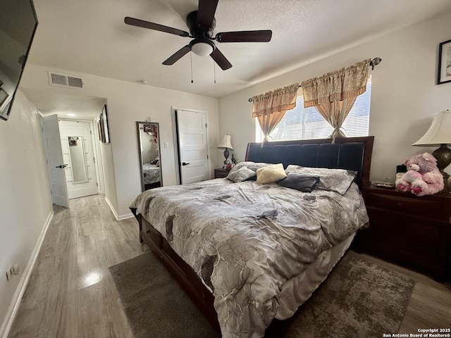 bedroom featuring visible vents, baseboards, wood finished floors, and a ceiling fan