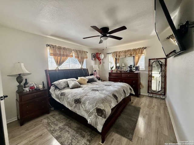 bedroom with baseboards, a textured ceiling, and light wood finished floors