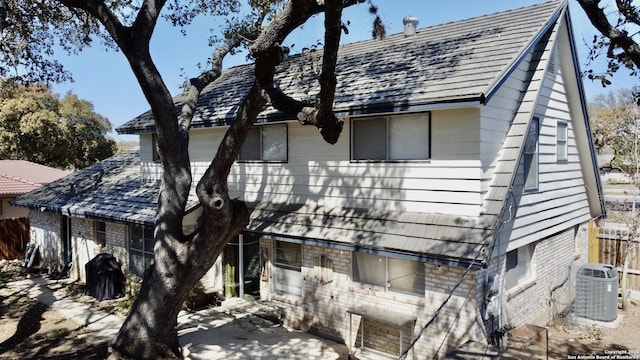 view of side of home with cooling unit, fence, and brick siding