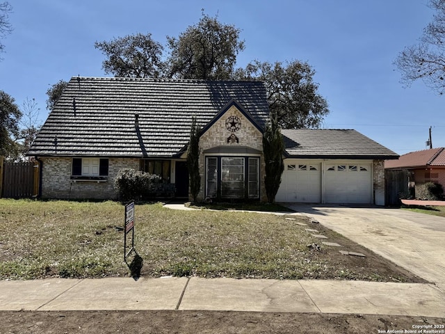 view of front of house with driveway, a tile roof, stone siding, a garage, and brick siding