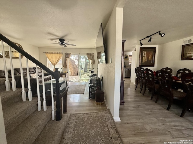 interior space featuring visible vents, a textured ceiling, wood finished floors, ceiling fan, and stairs