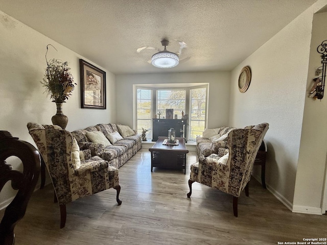 living area with wood finished floors, baseboards, and a textured ceiling