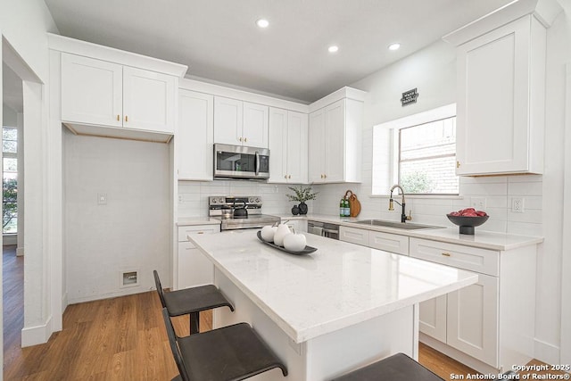 kitchen with a sink, decorative backsplash, appliances with stainless steel finishes, and white cabinetry