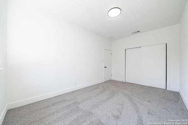 unfurnished bedroom featuring a closet, visible vents, carpet flooring, and baseboards