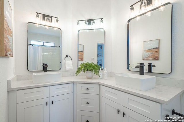 full bathroom with curtained shower, double vanity, and a sink