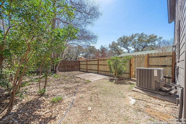 view of yard with central AC unit and a fenced backyard