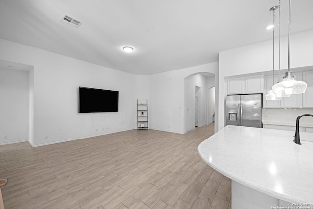 10619 Revolver Trl, San Antonio, TX 78254 - living area featuring arched walkways, visible vents, light wood finished floors, and baseboards