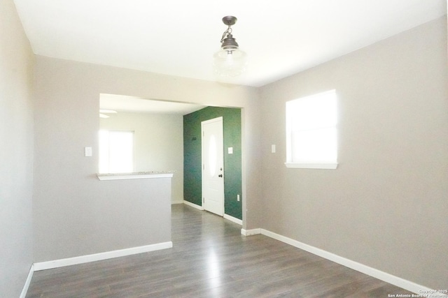 spare room with dark wood-type flooring and baseboards