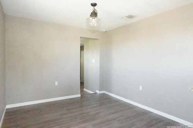 empty room featuring visible vents, baseboards, and dark wood-style floors