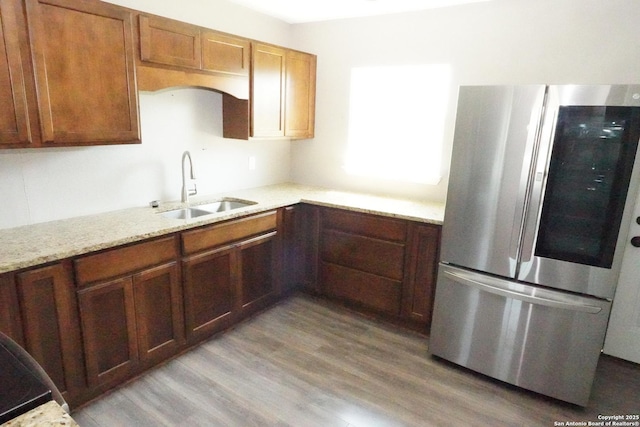 kitchen featuring a sink, light stone counters, wood finished floors, and smart refrigerator