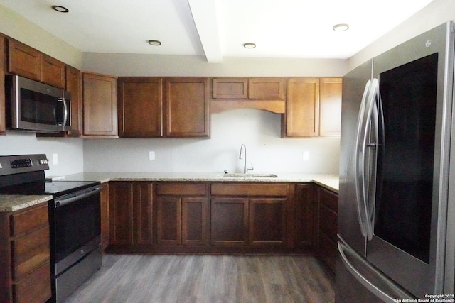 kitchen featuring light countertops, beam ceiling, appliances with stainless steel finishes, wood finished floors, and a sink