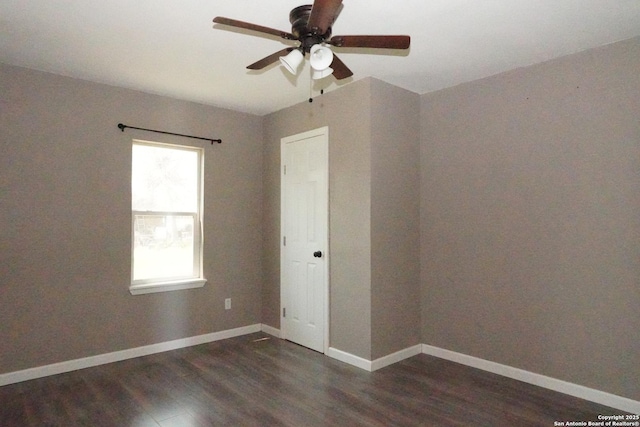 empty room with dark wood finished floors, a ceiling fan, and baseboards