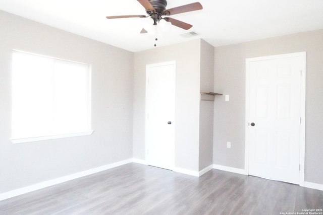 unfurnished bedroom with wood finished floors, visible vents, a closet, and baseboards