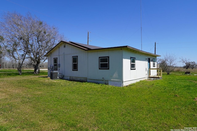 view of side of home featuring a yard and central AC