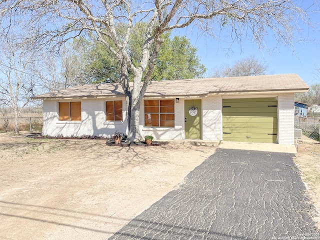 ranch-style home with a garage, brick siding, driveway, and fence