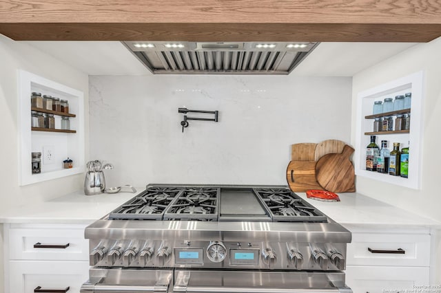 kitchen featuring built in shelves, ventilation hood, light countertops, stainless steel stove, and white cabinets