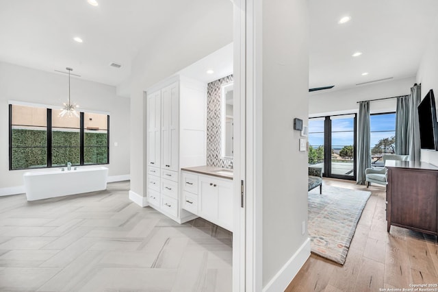 full bathroom featuring recessed lighting, a freestanding tub, baseboards, and vanity