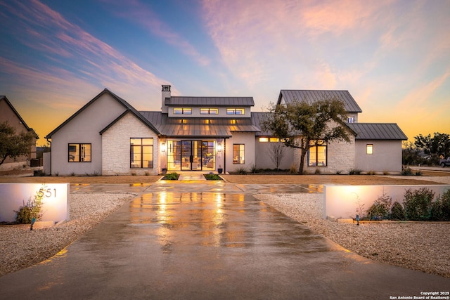 modern farmhouse featuring metal roof, stone siding, french doors, and a standing seam roof