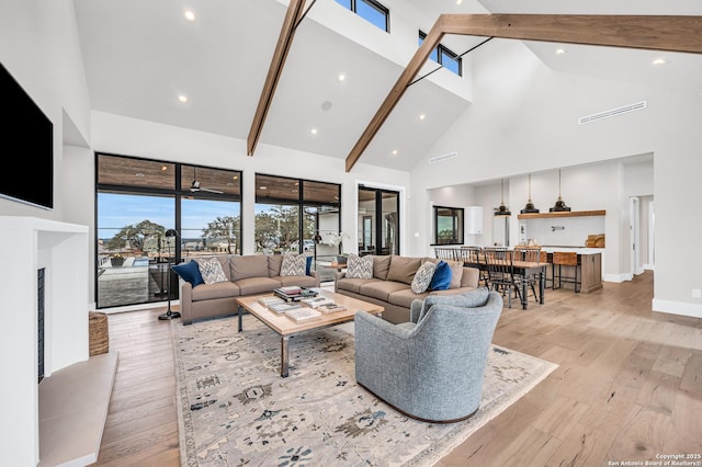 living area featuring beamed ceiling, high vaulted ceiling, light wood-style flooring, recessed lighting, and baseboards