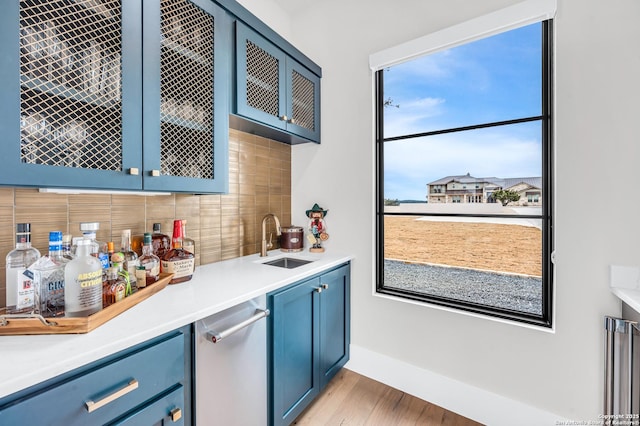 bar with baseboards, a sink, indoor wet bar, light wood-style floors, and tasteful backsplash