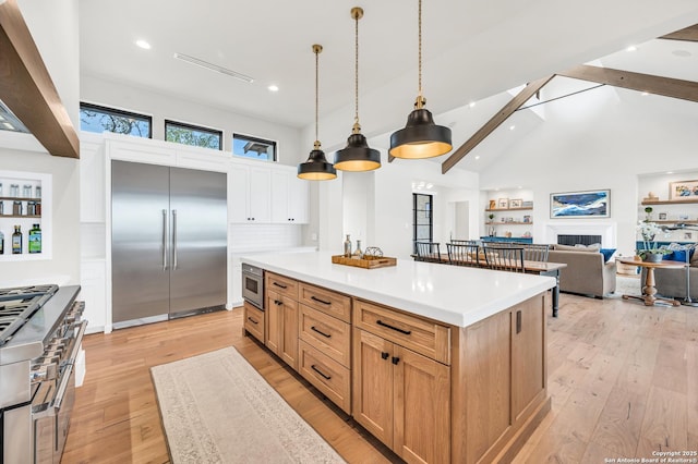 kitchen featuring beam ceiling, high vaulted ceiling, light wood-style floors, light countertops, and high end appliances