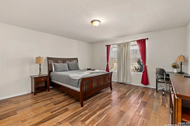 bedroom with a textured ceiling, baseboards, and hardwood / wood-style flooring