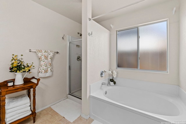 bathroom with a bath, tile patterned flooring, a stall shower, and baseboards