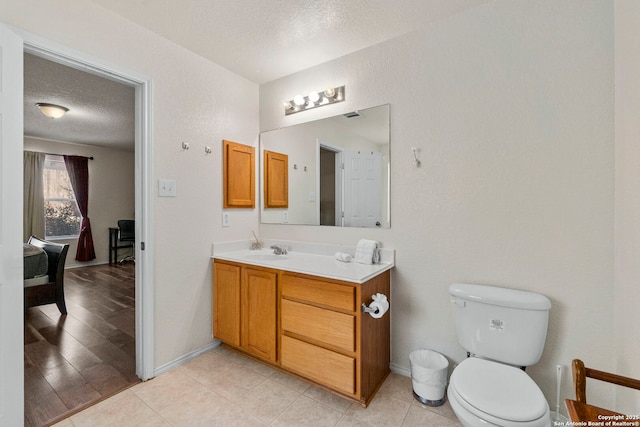 bathroom with toilet, a textured ceiling, vanity, and baseboards