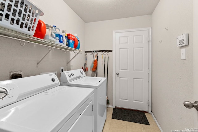 laundry room with washing machine and clothes dryer, baseboards, laundry area, light tile patterned flooring, and a textured ceiling