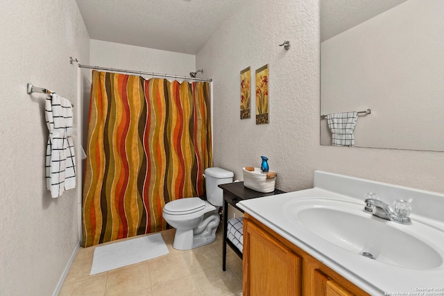 bathroom with tile patterned floors, a shower with curtain, toilet, vanity, and a textured wall