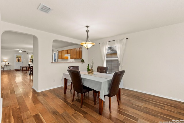 dining area featuring hardwood / wood-style flooring, visible vents, arched walkways, and baseboards