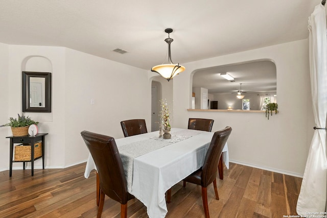 dining space with arched walkways, visible vents, baseboards, and wood finished floors