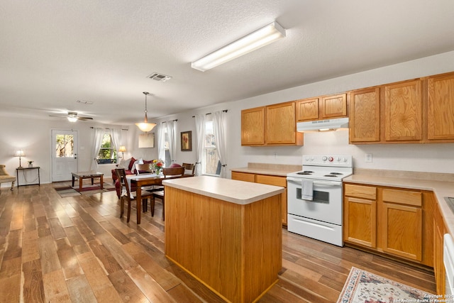 kitchen featuring visible vents, light wood-type flooring, under cabinet range hood, white electric stove, and light countertops