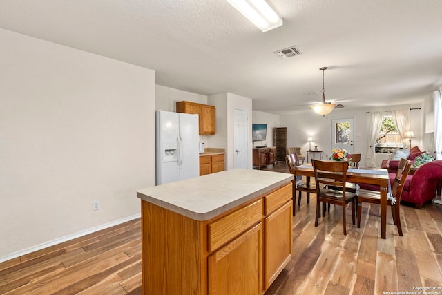 kitchen with visible vents, open floor plan, light wood-style floors, white fridge with ice dispenser, and light countertops