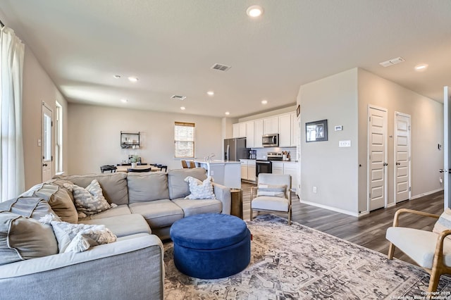 living room with dark wood-style floors, visible vents, recessed lighting, and baseboards