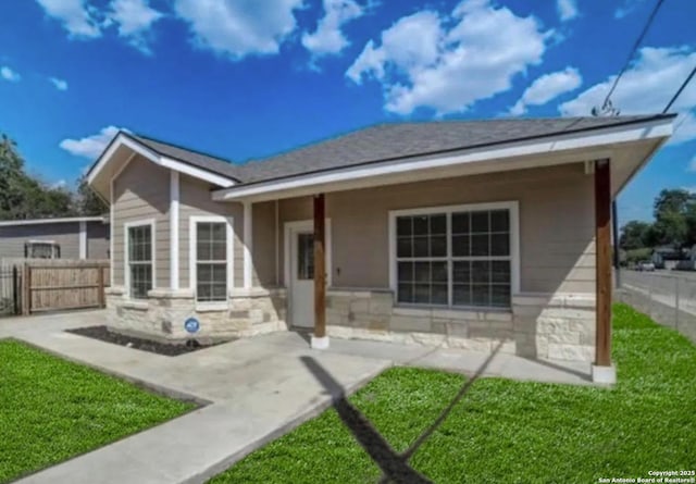 back of property featuring a yard, stone siding, a patio area, and fence