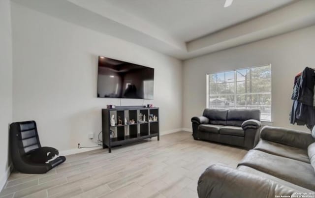 living room with a raised ceiling, baseboards, and wood finished floors