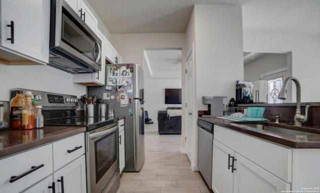 kitchen featuring dark countertops, white cabinets, appliances with stainless steel finishes, and a sink