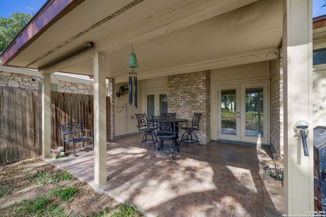 view of patio with french doors, outdoor dining space, and fence