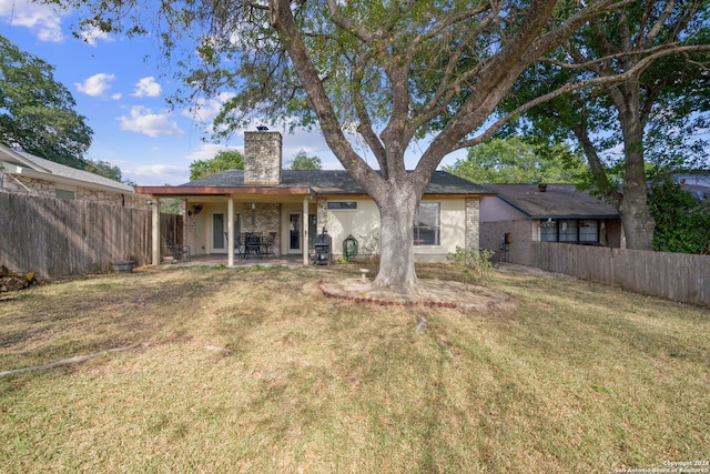 back of house with a patio, a yard, stucco siding, a chimney, and fence private yard